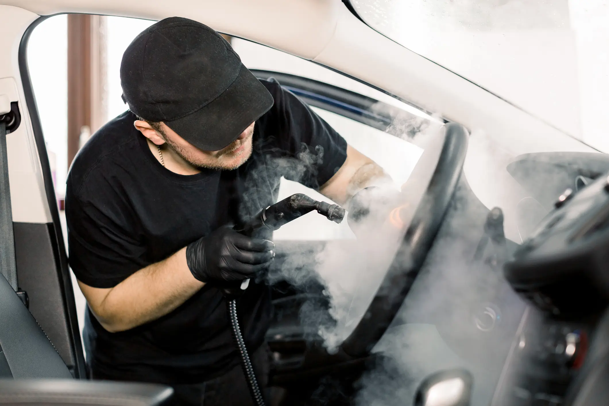 Person steam cleaning a car interior.