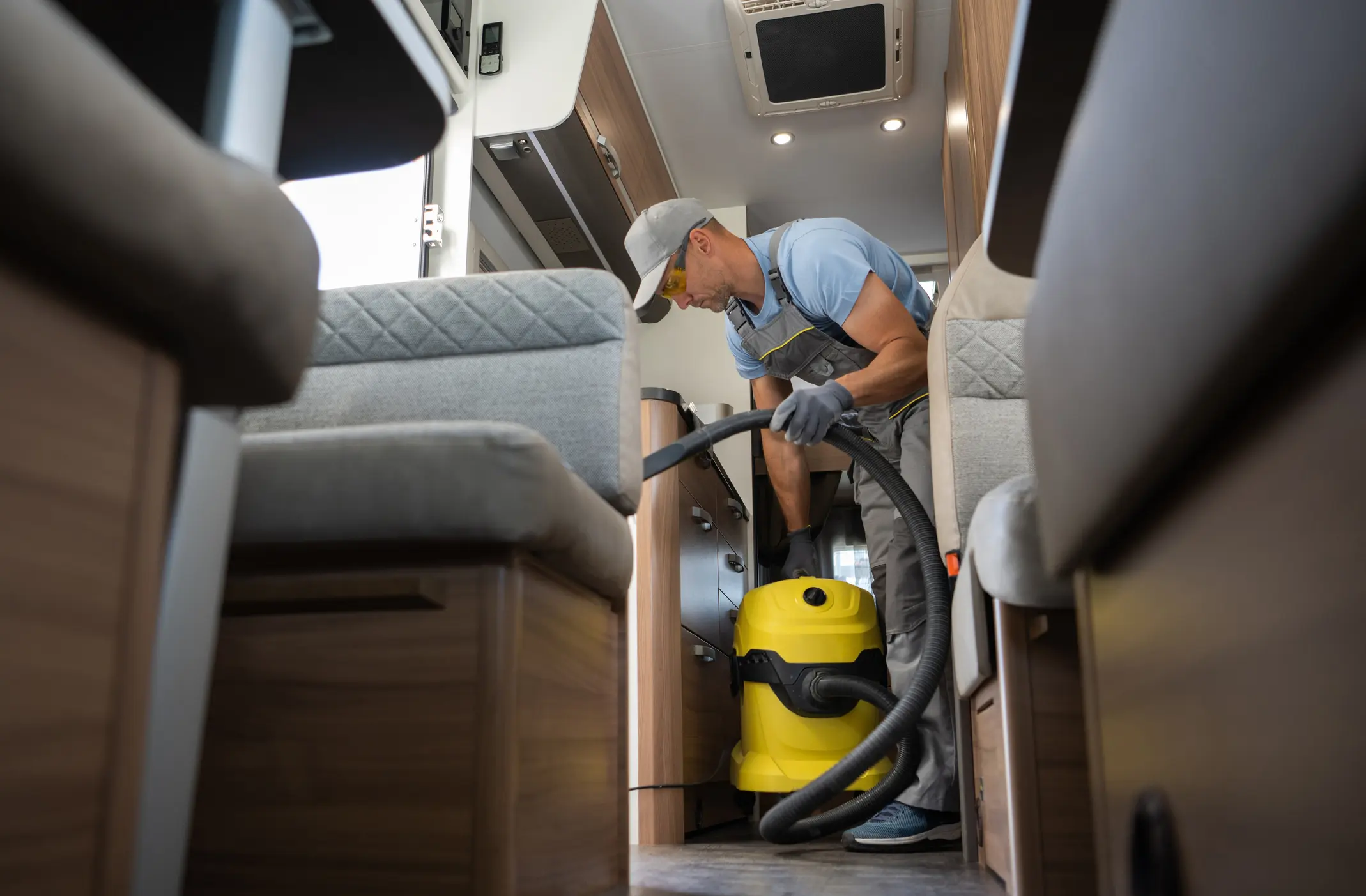Man vacuuming inside a motorhome with equipment.