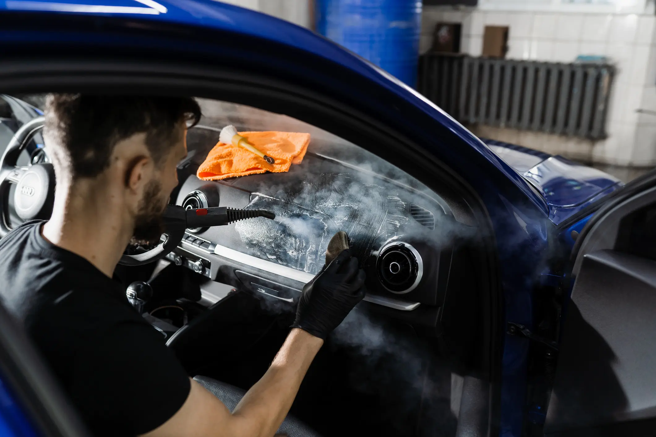 Man cleaning car interior with steam.